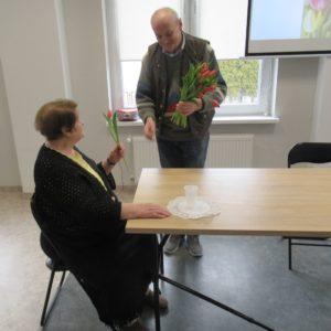 Senior dziennego domu wręcza Seniorce tulipana z okazji Dnia Kobiet