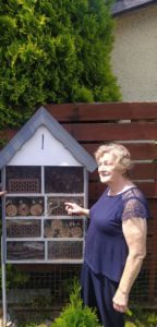 seniorka stoi przed domkiem dla owadów wykonanym przez seniorów Dziennego Domu