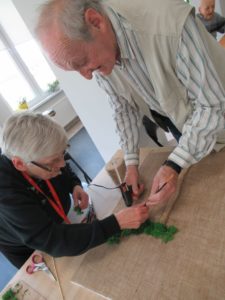 seniorzy Dziennego Domu Pomocy przygotowują kompozycję z mchu