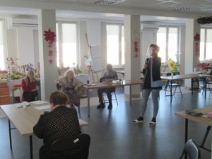 opiekun Dziennego Domu Pomocy dla Osób Starszych w Jaśle prowadzi zajęcia dla seniorów w sali Dziennego