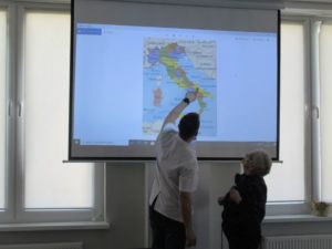 opiekun Dziennego Domu Pomocy, wspólnie z seniorką oglądają mapę Włoch,podczas prowadzonych zajęć.