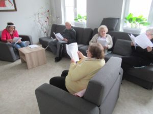 opiekun wspólnie z uczestnikami czyta wiersze w sali Dziennego Domu Pomocy
