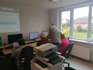 prowadzący warsztaty komputerowe tłumaczy seniorom Dziennego Domu Pomocy w Jaśle zasady obsługi komputera
