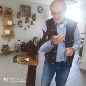 senior Dziennego Domu Pomocy dla Osób Starszych w Jaśle maluje drewnianą donicę ogrodową-jelonka