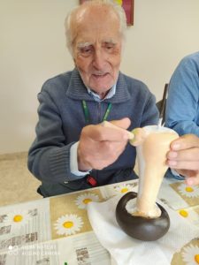 senior Dziennego Domu Pomocy dla Osób Starszych w Jaśle maluje farbą grzyb z cementu