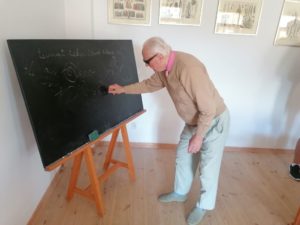 senior Dziennego Domu Pomocy pisze na tablicy w Muzeum Szkoły Ludowej w Żarnowcu