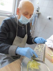 senior Dziennego Domu Pomocy w Jaśle przygotowuje jabłka na szarlotkę w kuchni Dziennego Domu
