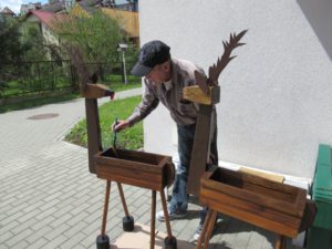 senior Dziennego Domu maluje drewniane doniczki ogrodowe-jelonki