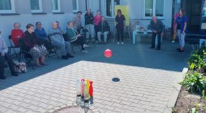 senior Dziennego Domu rzuca piłką w kręgle na zawodach zorganizowanych w Dziennym Domu