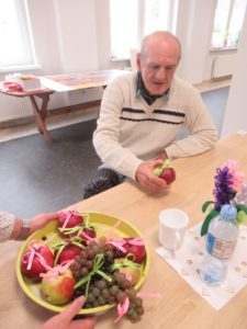 senior częstuje się jabłkiem na zajęciach w Dziennym Domu Pomocy w Jaśle