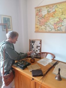 seniorka Dziennego Domu Pomocy ogląda liczydło w Muzeum Szkoły Ludowej w Żarnowcu