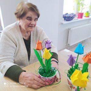 seniorka Dziennego Domu Pomocy prezentuje tulipany wykonane przez seniorów na zajęciach arteterapii