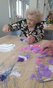 seniorka Dziennego Domu Pomocy w Jaśle naciąga rajstopy na formę z drutu