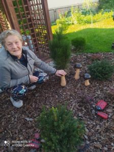 seniorka Dziennego Domu Pomocy w Jaśle prezentuje grzyby z cementu w ogrodzie Dziennego Domu