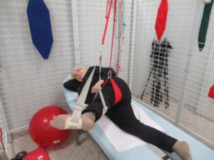 seniorka Dziennego Domu Pomocy w Jaśle wykonuje ćwiczenia czynne w odciążeniu kończyn dolnych