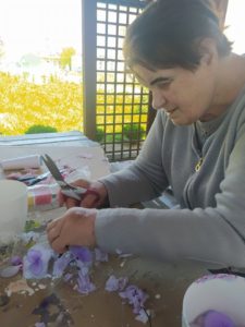 seniorka Dziennego Domu Pomocy wycina z kolorowych rajstop elementy płatków storczyka