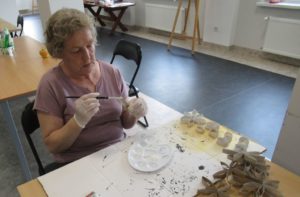seniorka Dziennego Domu maluje papierowe elementy podczas zajęć terapii zajęciowej