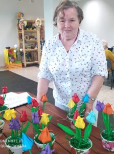 seniorka prezentuje tulipany wykonane przez seniorów na zajęciach arteterapii w Dziennym Domu Pomocy