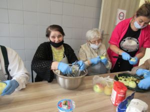 seniorki Dziennego Domu Pomocy wspólnie z opiekunem przygotowują szarlotkę na zajęciach kulinarnych