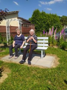 seniorki odpoczywają na ławeczce, w ogrodzie Dziennego Domu Pomocy dla Osób Starszych w Jaśle