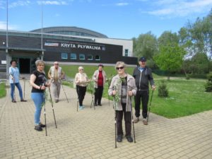 seniorzy Dziennego Domu Pomocy spacerują z kijkami do nordic-walking