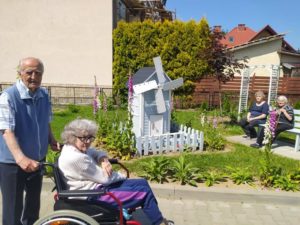 seniorzy Dziennego Domu Pomocy spędzają czas na świeżym powietrzu, w ogrodzie Dziennego Domu