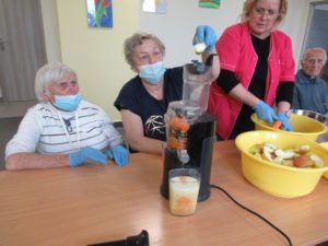 seniorzy Dziennego Domu Pomocy wspólnie z opiekunem przygotowują sok marchwiowo-jabłkowy na zajęciach kulinarnych (2)