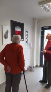 seniorzy oglądają obrazy wykonane techniką string-art przez uczestników Dziennego Domu Pomocy dla Osób Starszych w Jaśle