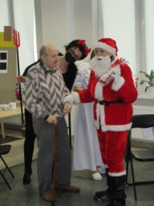 Mikołaj wręcza prezent seniorowi na sali Dziennego Domu Pomocy dla Osób Sarszych w Jaśle
