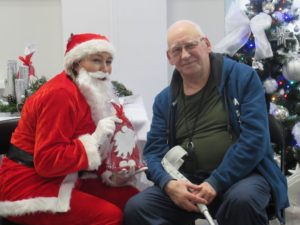 Mikołaj wręcza prezent seniorowi na sali Dziennego Domu Pomocy dla Osób Starszych w Jaśle