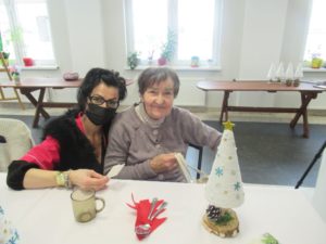 opiekunka Dziennego Domu Pomocy w Jaśle składa życzenia seniorce podczas Spotkania wigilijnego