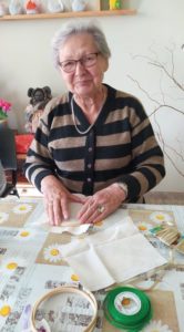 seniorka Dziennego Domu Pomocy dla Osób Starszych w Jaśle naciąga materiał na drewniany tamborek