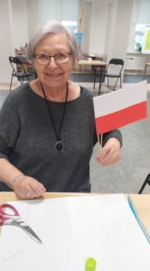 seniorka Dziennego Domu Pomocy trzyma w ręce polską flagę