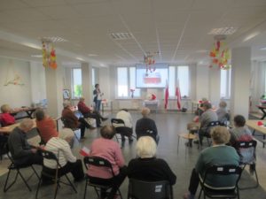 seniorzy Dziennego Domu Pomocy słuchają prelekcji z okazji Narodowego Święta Odzyskania przez Polskę Niepodległości