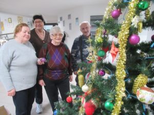 seniorzy ubierają choinkę w Dziennym Domu Pomocy dla Osób Starszych w Jaśle