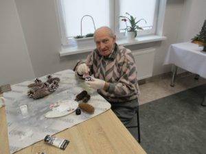 uczestnik Dziennego Domu Pomocy w Jaśle maluje szyszki na zajęciach terapii zajęciowej