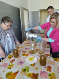 pracownicy wspólnie z seniorką przygotowują syrop z mniszka lekarskiego w kuchni Dziennego Domu Pomocy