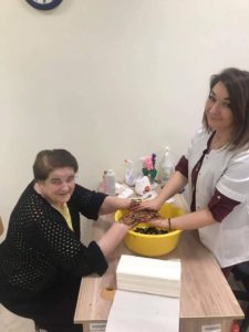 pracownik Dziennego Domu Pomocy wykonuje peeling dłoni w Dniu Kobiet