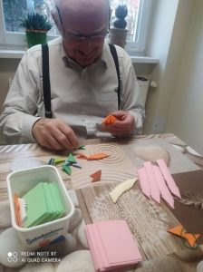 senior Dziennego Domu Pomocy w Jaśle składa papierowe elementy origami