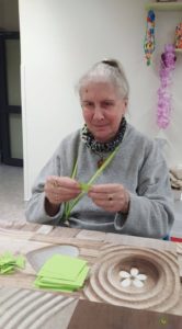 seniorka Dziennego Domu Pomocy dla osób Starszych w Jaśle składa papierowe elementy origami