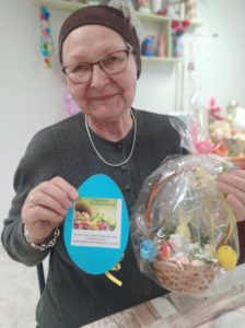 seniorka Dziennego Domu Pomocy prezentuje koszyczek oraz świąteczne życzenia przygotowane przez przedszkolaków