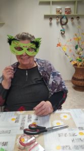 seniorka Dziennego Domu Pomocy prezentuje maskę karnawałową wykonaną na zajęciach terapii zajęciowej