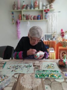 seniorka Dziennego Domu Pomocy przygotowuje stroik świąteczny na zajęciach terapii zajęciowej