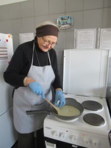 seniorka Dziennego Domu Pomocy smaży naleśniki na zajęciach kulinarnych