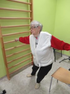 seniorka Dziennego Domu Pomocy wykonuje ćwiczenia rozciągające przy drabince