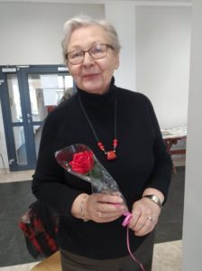seniorka prezentuje różę otrzymaną w Dziennym Domu Pomocy, z okazji Dnia Kobiet
