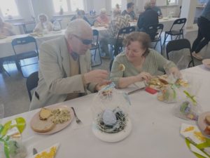 seniorzy Dziennego Domu Pomocy delektują się świątecznymi potrawami podczas śniadania wielkanocnego
