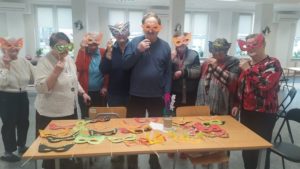 uczestnicy Dziennego Domu Pomocy prezentują maski karnawałowe wykonane na zajęciach terapii zajęciowej