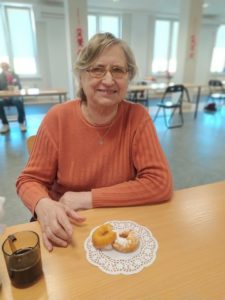 uczestniczka Dziennego Domu Pomocy w Jaśle częstuje sie w Tłusty Czwartek oponkami przygotowanymi przez seniorki Dzienneg~1