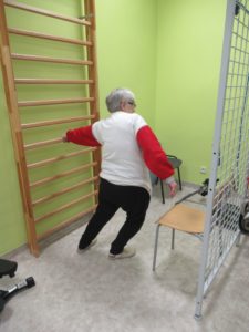 uczestniczka Dziennego Domu Pomocy w Jaśle wykonuje ćwiczenia rozciągające przy drabince